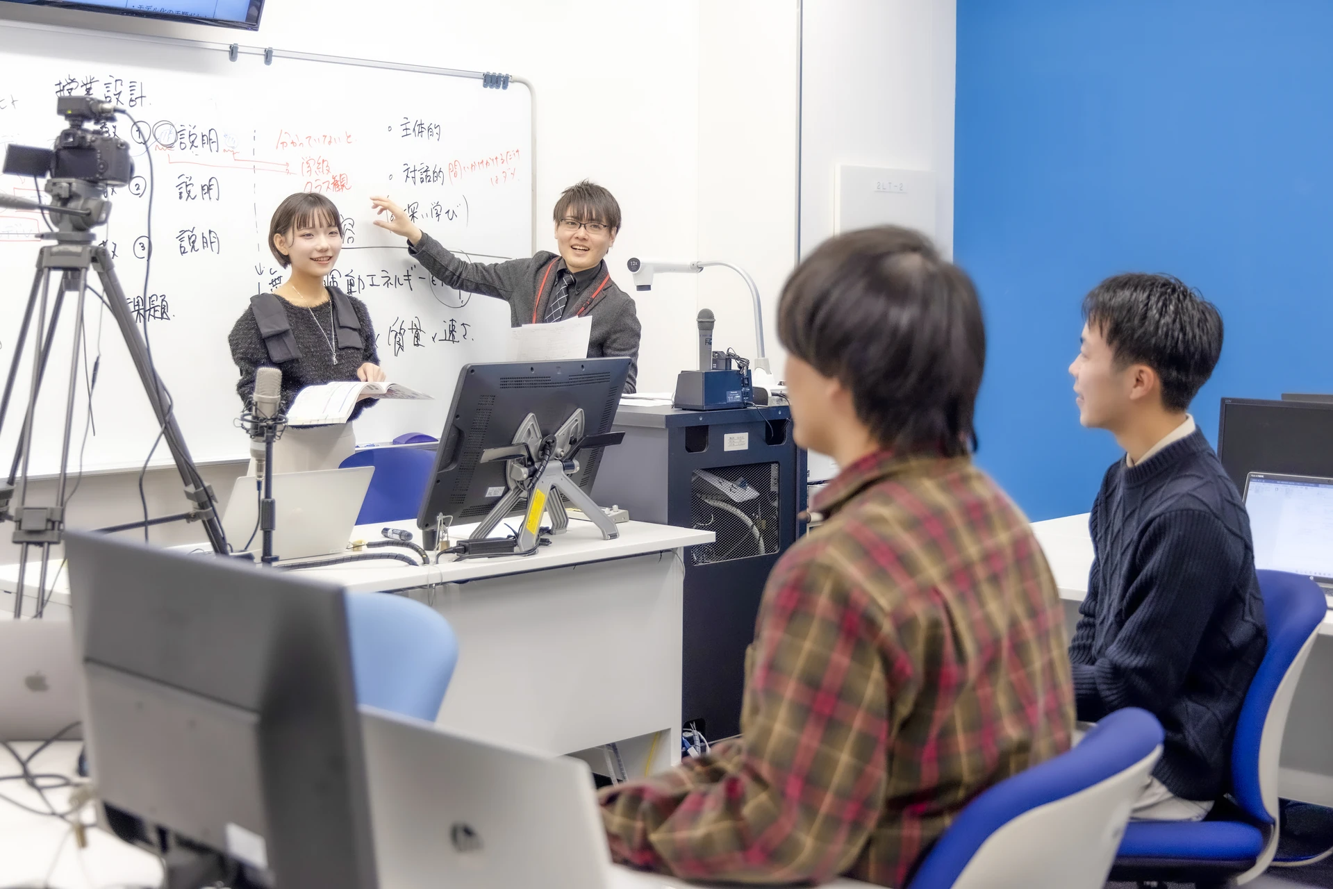情報科教育法の授業で、学生が模擬授業を行い、教員と受講者が意見を交わしている様子